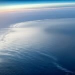 Battery-electric aircraft flying at sunrise over ocean — green technology breakthroughs 2026